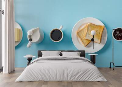 Top view of cup of coffee, milk, butter, jam and two toasts on white plate on blue background Wall mural