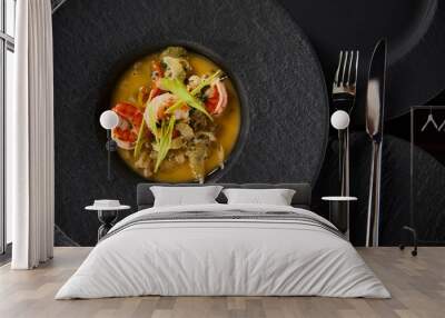 top view of delicious restaurant soup with shrimps in black plate with cutlery Wall mural