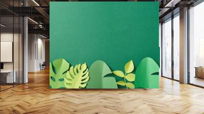 top view of exotic paper cut palm leaves on green background with copy space Wall mural