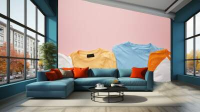 top view of folded color t-shirts on pink background Wall mural