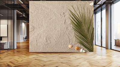 top view of green palm leaf and arranged seashells on sand Wall mural