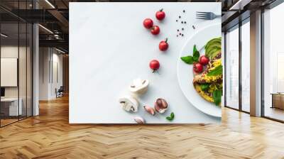 top view of homemade omelette with cherry tomatoes, avocado pieces and cutlery on white marble surface Wall mural