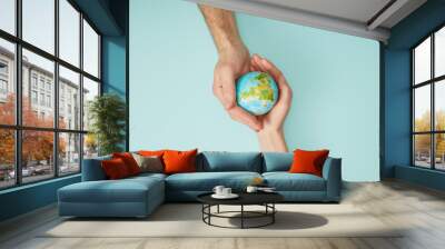 top view of man and woman holding planet model on turquoise background, earth day concept Wall mural