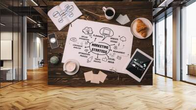 top view of paper with marketing strategy, business supplies, croissant and coffee cup on wooden table Wall mural