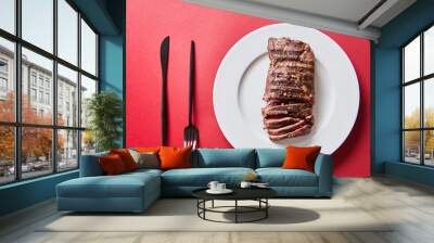 top view of tasty grilled steak served on plate with cutlery on red background Wall mural