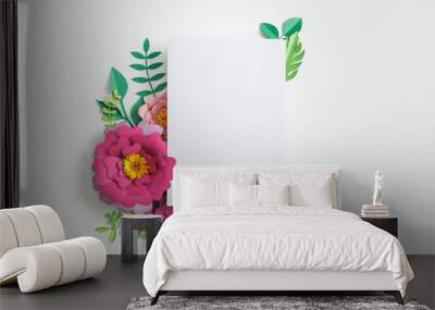 top view of white blank card near pink paper flowers and green leaves on grey background Wall mural