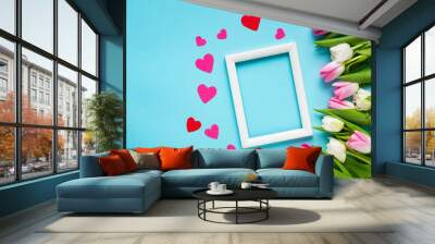 Top view of white empty frame with paper hearts and tulips on blue background Wall mural