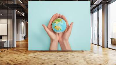 top view of woman holding planet model on turquoise background, earth day concept Wall mural