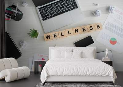 top view of workplace with business documents, laptop, smartphone and alphabet cubes with wellness word Wall mural