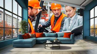 two workers and inspector using forklift machine in storehouse Wall mural