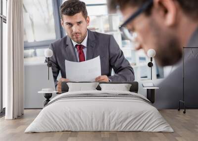 unsatisfied boss looking at upset colleague at business meeting Wall mural