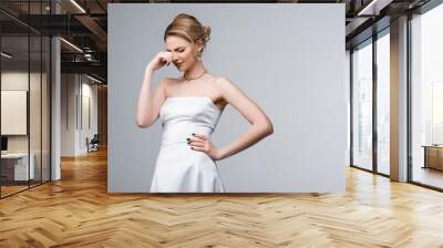 upset bride in white wedding dress standing with hand on hip and crying isolated on grey Wall mural