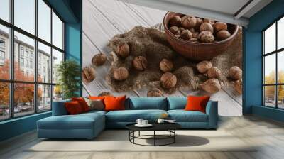 walnuts with wooden bowl and sackcloth on white wooden background Wall mural