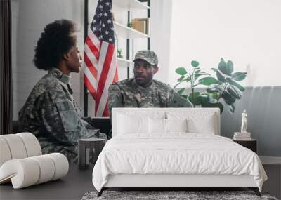 Woman and man in army uniform talking on sofa at home Wall mural