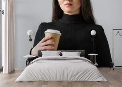 young asian woman in stylish black turtleneck and glasses holding paper cup isolated on grey Wall mural