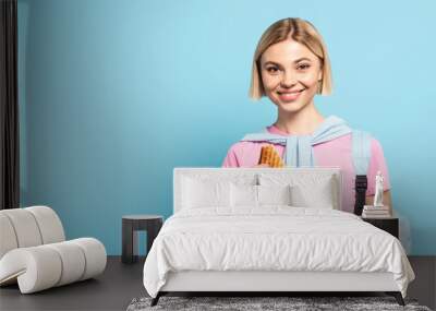 young blonde student holding paper bag and toast bread on blue Wall mural