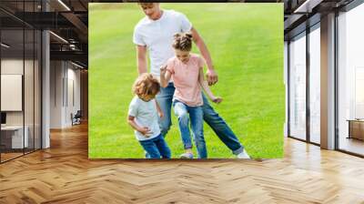 young father with cute little children playing soccer on green grass in park Wall mural