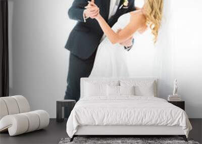 young groom in elegant suit dancing with happy bride isolated on white Wall mural