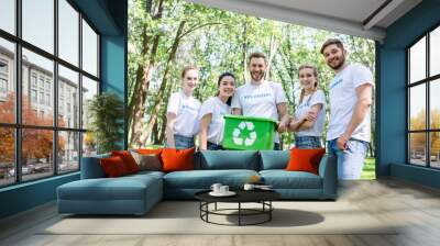 young happy volunteers with green recycling box in park Wall mural