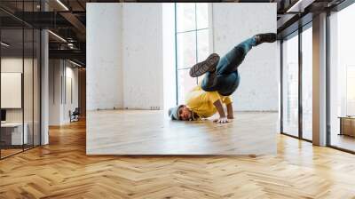 young man in hat breakdancing in dance studio Wall mural