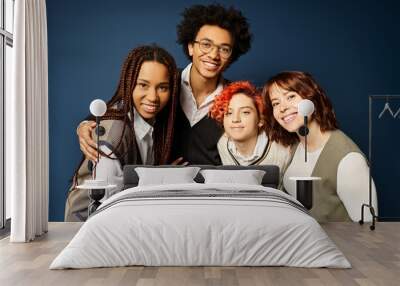 Young multicultural friends, including a nonbinary person, stand together in stylish attire against a dark blue background. Wall mural