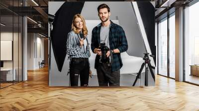 young photographers with professional equipment standing together and smiling at camera in photo studio Wall mural