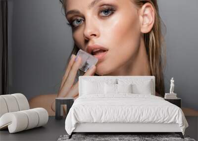 young sensual woman holding ice cube near lips isolated on grey Wall mural