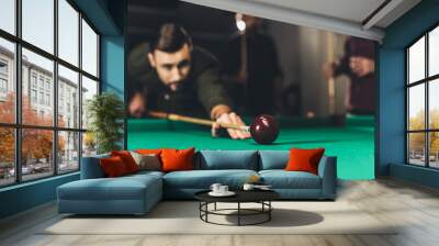 young successful handsome man playing in russian pool at bar with friends Wall mural