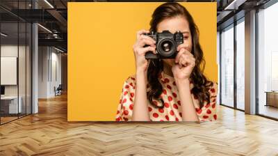 young woman taking phone on digital camera isolated on yellow Wall mural