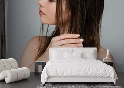 young woman with bare shoulders applying foam on wet hair isolated on grey Wall mural