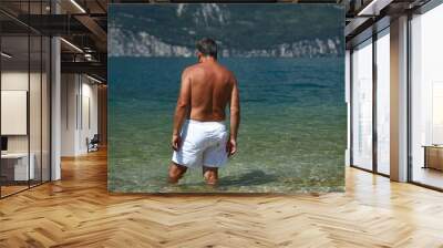 Adult man going for a swim in a lovely lake (Garda lake, Italy) Wall mural