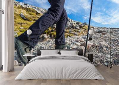 Pretty, young female hiker going uphill, crossing a snow field Wall mural