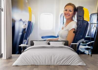 Pretty, young female passenger on board of an aircraft Wall mural