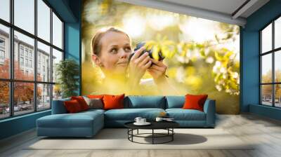 Pretty female amateur photographer taking photos outdoors Wall mural