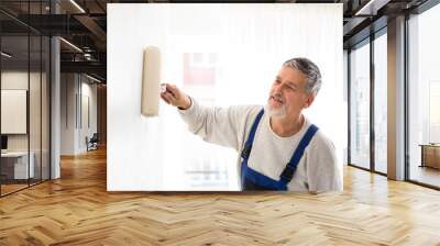 Senior man painting a wall in his home Wall mural