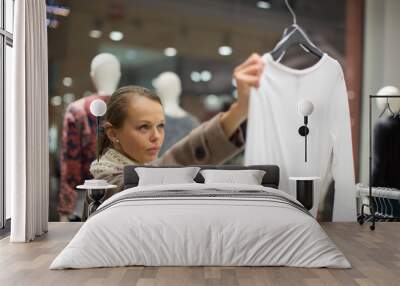 Young woman shopping in a fashion store (color toned image; shallow DOF) Wall mural