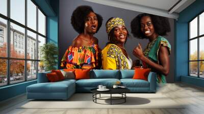 Three young beautiful African fashion models have fun and laughing in traditional dress. Women from the Congo Republic, Ivory Coast, and Zimbabwe Wall mural