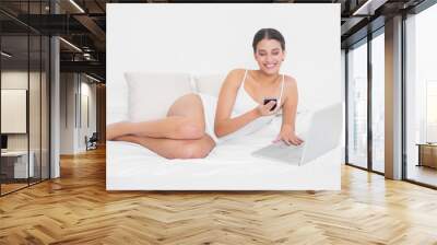 beautiful young brown haired model in white pajamas using a mobi Wall mural