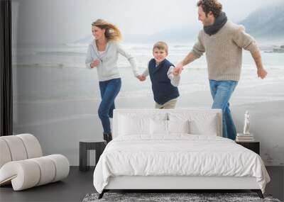 Happy family of three running at beach Wall mural