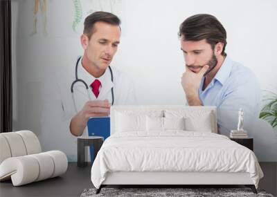 Male doctor discussing reports with patient at desk Wall mural