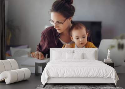 Young businesswoman working from home. Young mother working on lap top  at her home office. She working with her child. Wall mural