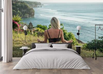 Portrait of young blonde woman meditates on the cliff with ocean view Wall mural