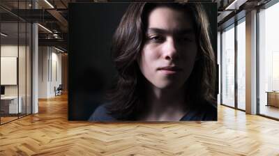 Portrait of young man with long hair in low key with Rembrandt lightning Wall mural