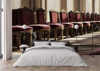 A row of kneeling pews, upholstered in rich burgundy velvet, invites congregants to join in prayer within a European cathedral. Wall mural