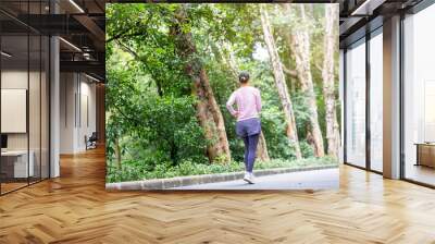 Back view of woman exercising and jogging in park Wall mural