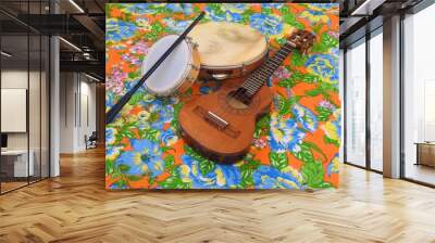 Three Brazilian musical instruments: cavaquinho, pandeiro (tambourine) and tamborim with drumstick on a colorful “chitao” fabric with floral prints. They are widely used in samba and pagode ensembles. Wall mural