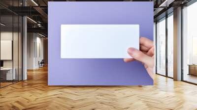 Hand is holding blank white card on a purple. Woman holding blank business card on violet background Wall mural