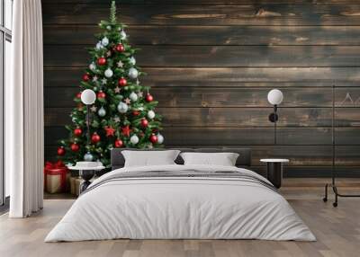 A decorated Christmas tree stands in front of a wood plank wall, with several wrapped gifts at its base Wall mural