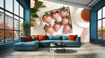 A delightful assortment of chocolate-covered strawberries is arranged next to a steaming cup of tea on a rustic table, creating a comforting atmosphere for relaxation Wall mural