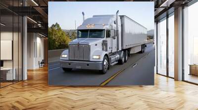 A large truck with a trailer navigates a highway, while blurred cars speed by beneath a vibrant blue sky and mountains Wall mural